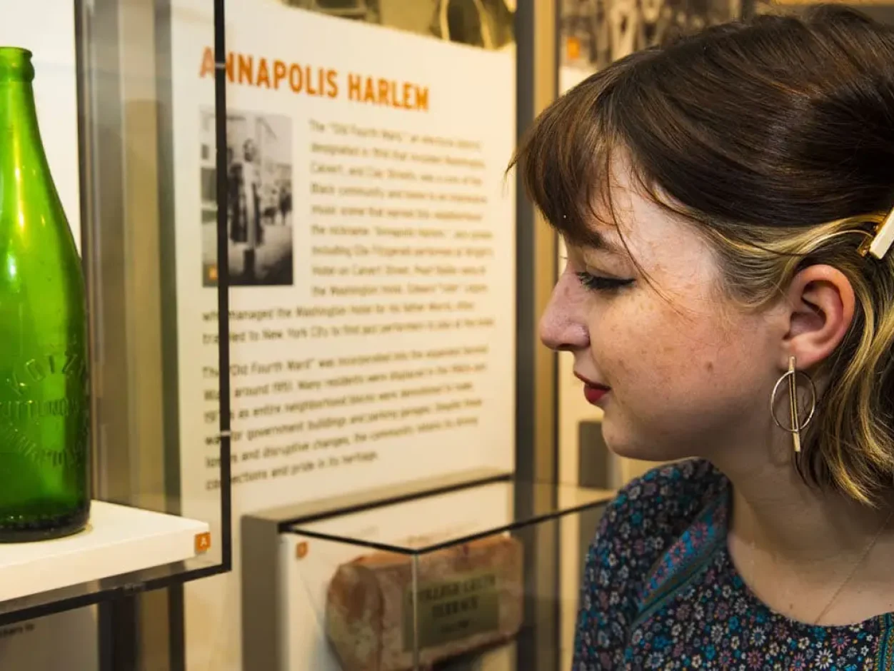 Young girl looking at green bottle in museum